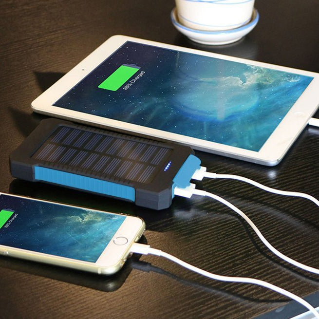 Solar power bank charging a smartphone and tablet on a dark surface