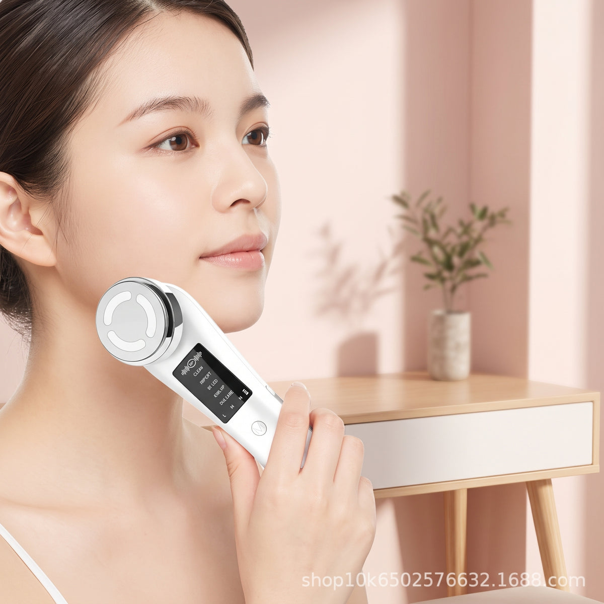 lifestyle: A NEW photorealistic photograph. A person with a calm expression is using the beauty device on their jawline, captured in a bright, modern bedroom vanity setting. The background features a simple, pale pink wall and a sleek, light-wood vanity table with a subtle, out-of-focus plant. Gentle, warm afternoon light softly illuminates the scene from the right, creating a serene and inviting mood. The beauty device is in active use, gently gliding along the subject's lower face. The camera is at a sli…